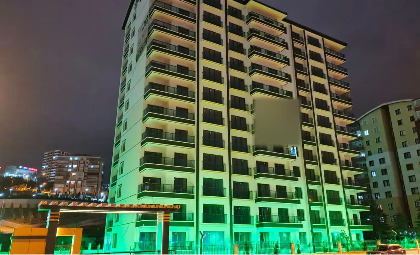 Yeşil ışıklarla aydınlatılmış yüksek katlı konut binası, gece görünümü