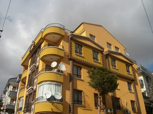 Sarı boyalı, yuvarlak balkonlu apartman